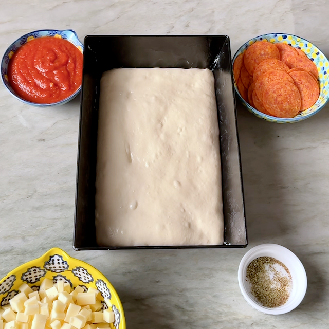 Detroit-Style pizza dough in an Ooni Detroit-Style Pizza pan fully proofed and ready to be topped and baked.